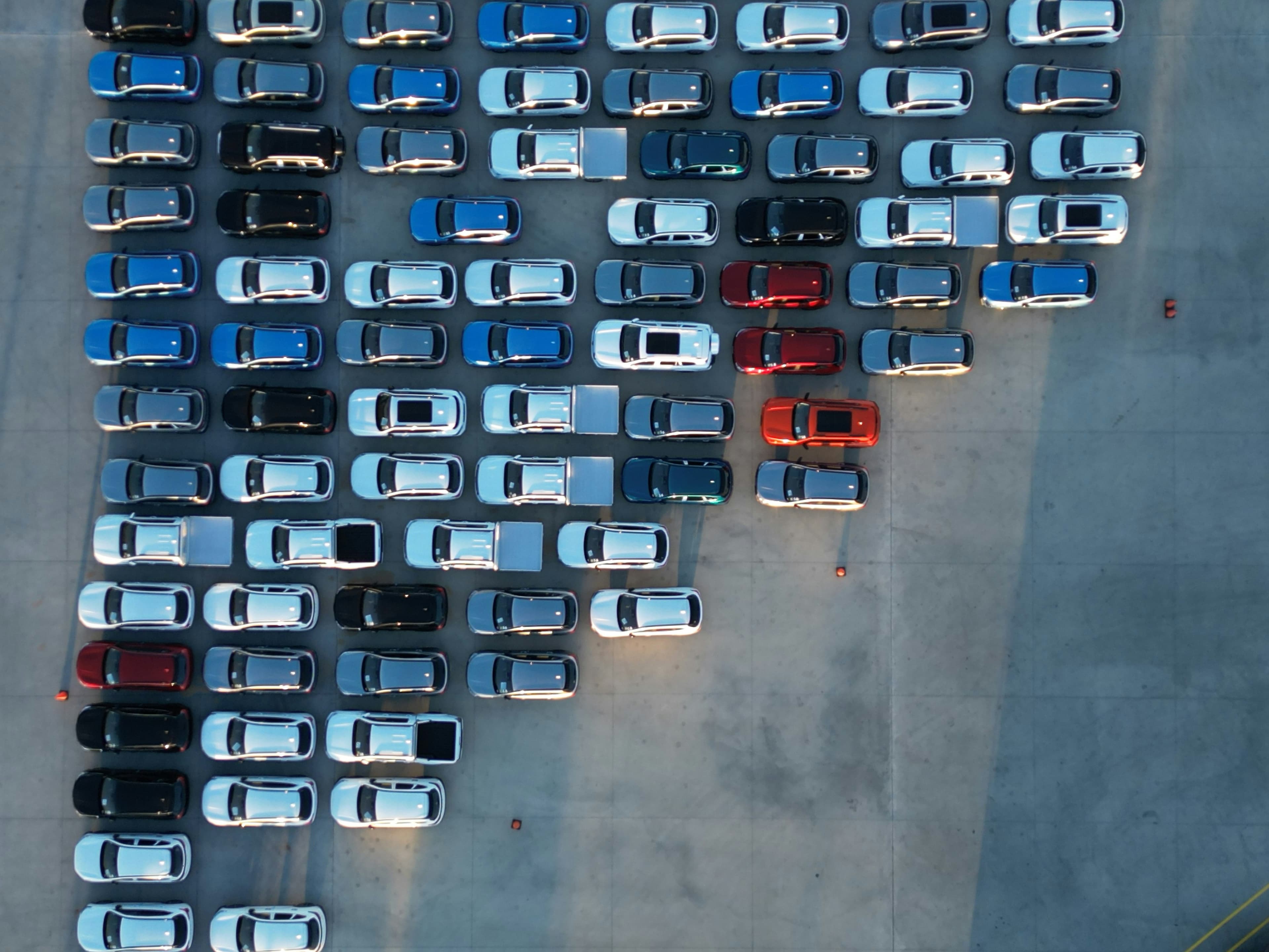 Used cars parked in rows on a dealer forecourt, seen from above